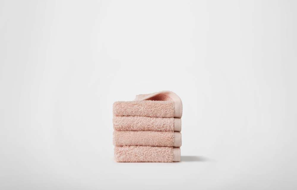 Stack of bath towels on wooden background. White and pink fluffy